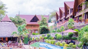 A resort with a pool, thatched-roof structures, and lush greenery. - Panorama Park Hotel (Naivasha)