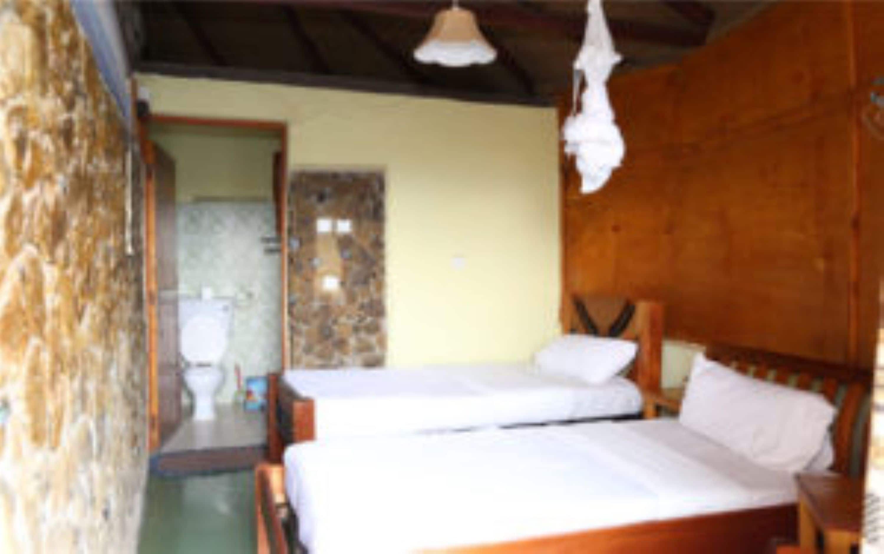A room with two wooden beds, a stone wall, and a wooden ceiling.