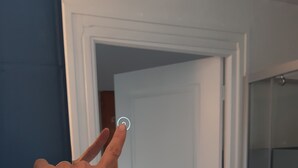 Une main appuyant sur un bouton situé sur un panneau de commande fixé au mur.