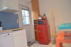 A compact kitchen with a red refrigerator, a microwave, and a wooden cabinet.