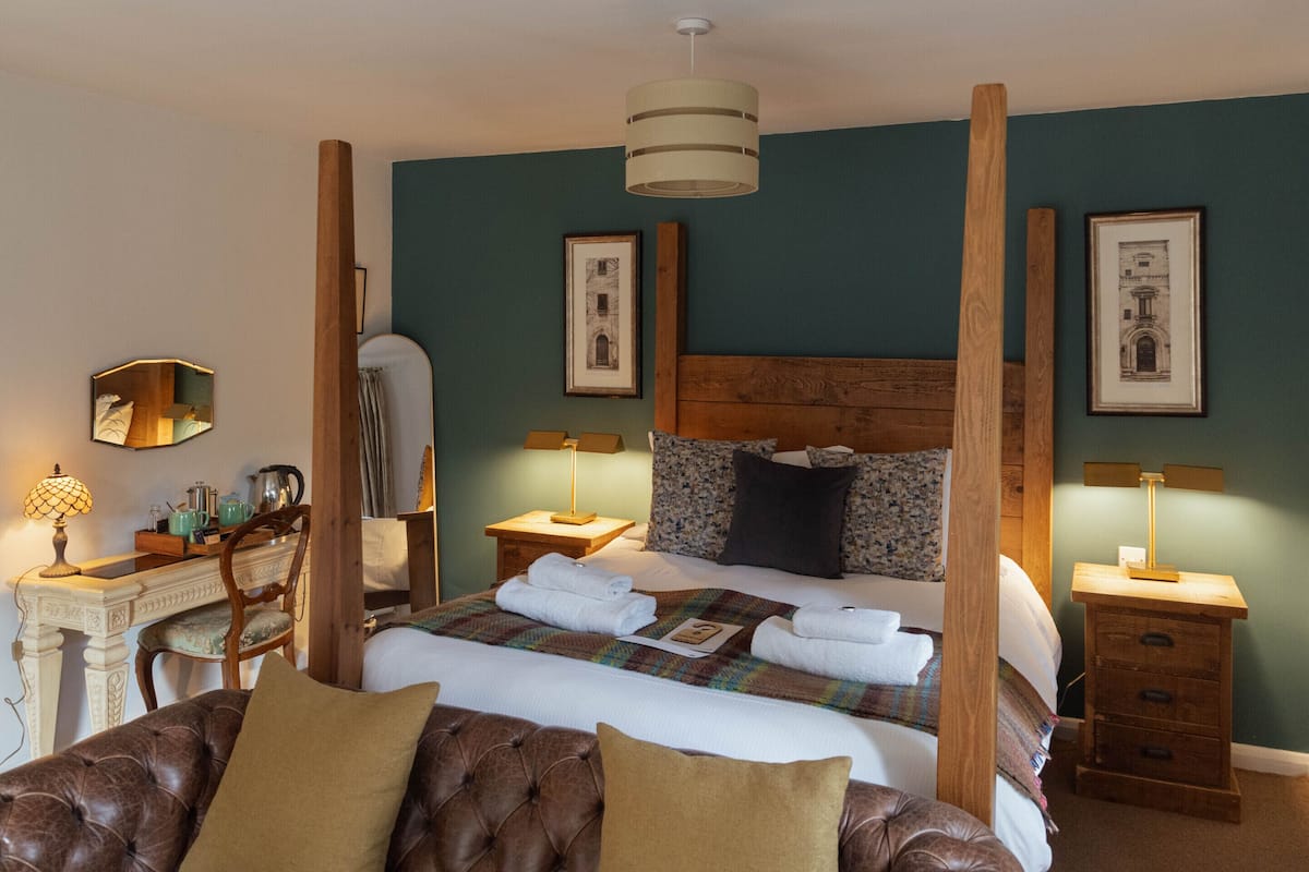 Quarto bem decorado com uma cama grande, cabeceira de madeira e mesa de cabeceira com abajur.