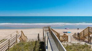 Una passerella in legno che conduce a una spiaggia con vista libera sull'oceano.