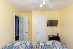 A bedroom with two beds, a ceiling fan, a TV, and a desk with a computer. - Topsail State of Mind - 4BR Oceanfront Home; Elevator; Covered Porch (Surf City)