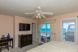 A bedroom with a bed, a ceiling fan, a TV, a dresser, a chair, and a balcony with a view of the ocean. - Topsail State of Mind - 4BR Oceanfront Home; Elevator; Covered Porch (Surf City)