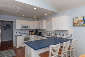 A kitchen with white cabinets, a blue countertop, and a microwave. - Topsail State of Mind - 4BR Oceanfront Home; Elevator; Covered Porch (Surf City)