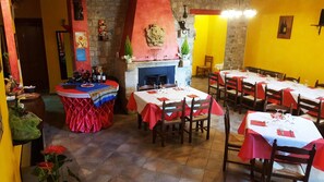 A restaurant with multiple tables, a fireplace, and a stone wall. - I Templari (Polizzi Generosa)