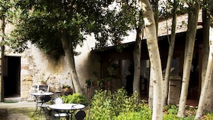 An outdoor patio with a table and chairs, surrounded by greenery and trees. - I Templari (Polizzi Generosa)
