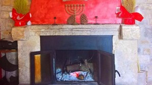 A stone fireplace with a red mantelpiece, a menorah, and decorative items. - I Templari (Polizzi Generosa)