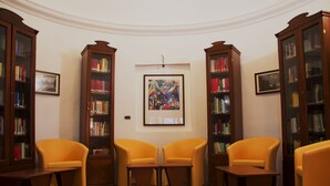 A library with bookshelves, two orange chairs, and a framed painting on the wall. - I Templari (Polizzi Generosa)