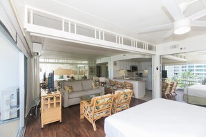 A spacious room with a large bed, a sofa, and a dining area with chairs. There is a kitchen area with a counter and a television. - Spacious One Bedroom Harbor View Condos at Ilikai Marina With Private Balcony (Honolulu)