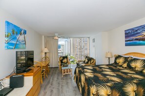 Une chambre d’hôtel avec un lit, un bureau, une télévision et des chaises.