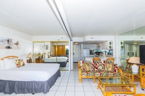 A hotel room with a bed, a sofa, a dining table, and a kitchen area visible through an open door. - Ilikai Tower 1 Bedroom City View Condos with Private Lanai & Free Wifi! (Honolulu)