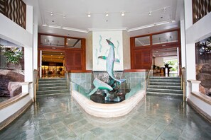 A lobby with a central fountain, a staircase, and a reception area. - Ilikai Tower 1 Bedroom City View Condos with Private Lanai & Free Wifi! (Honolulu)