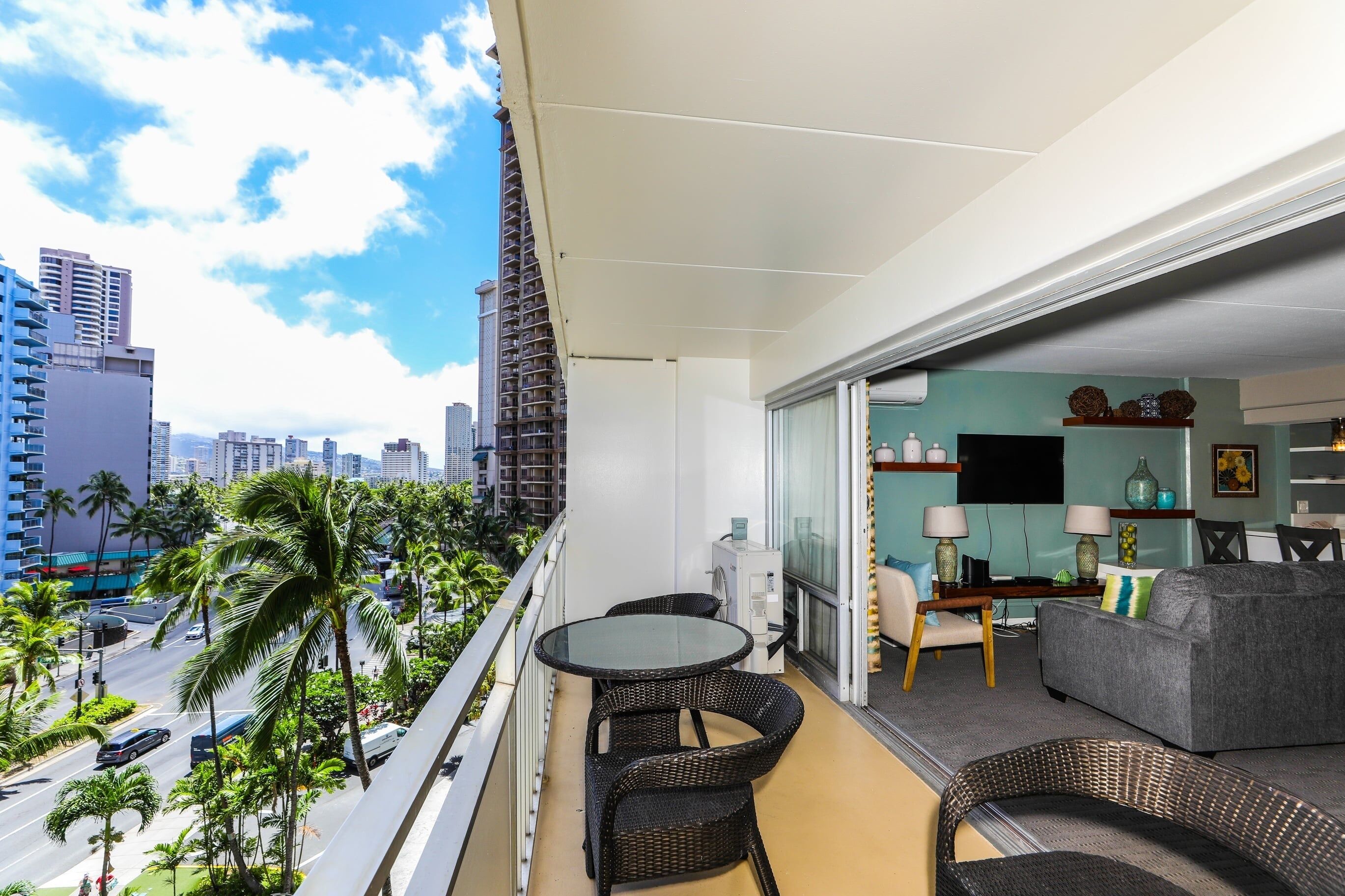 A balcony with a dining area, a sofa, and a TV in the living room.