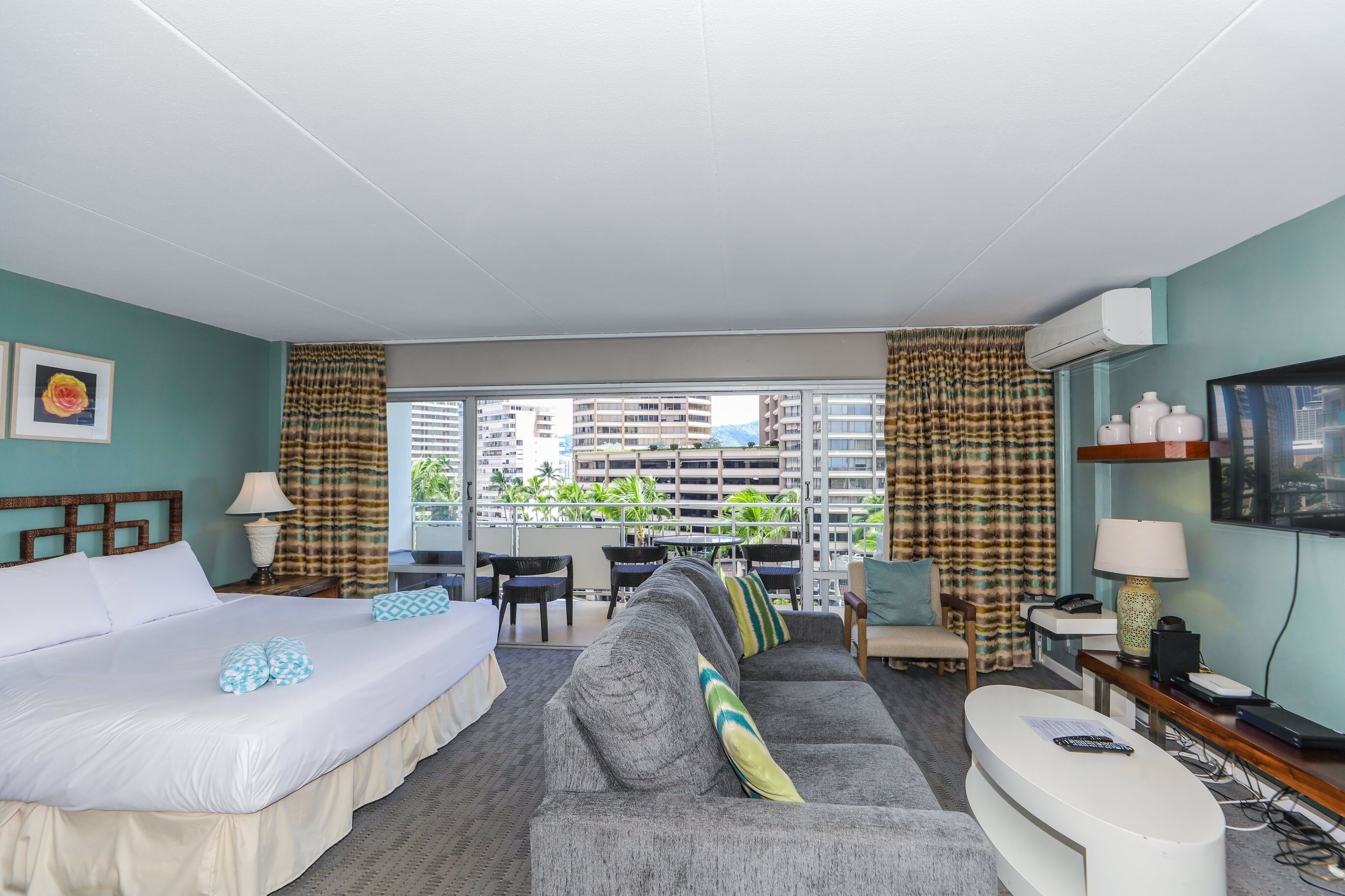 Une chambre d’hôtel avec un lit, un canapé et un balcon offrant une vue sur la ville.