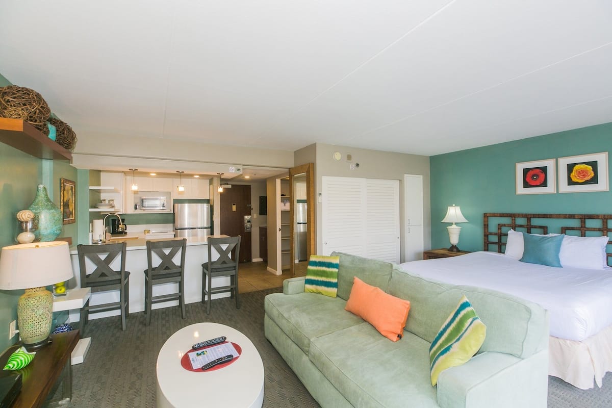 Una habitación de hotel con kitchenette, comedor, cama grande y sofá.