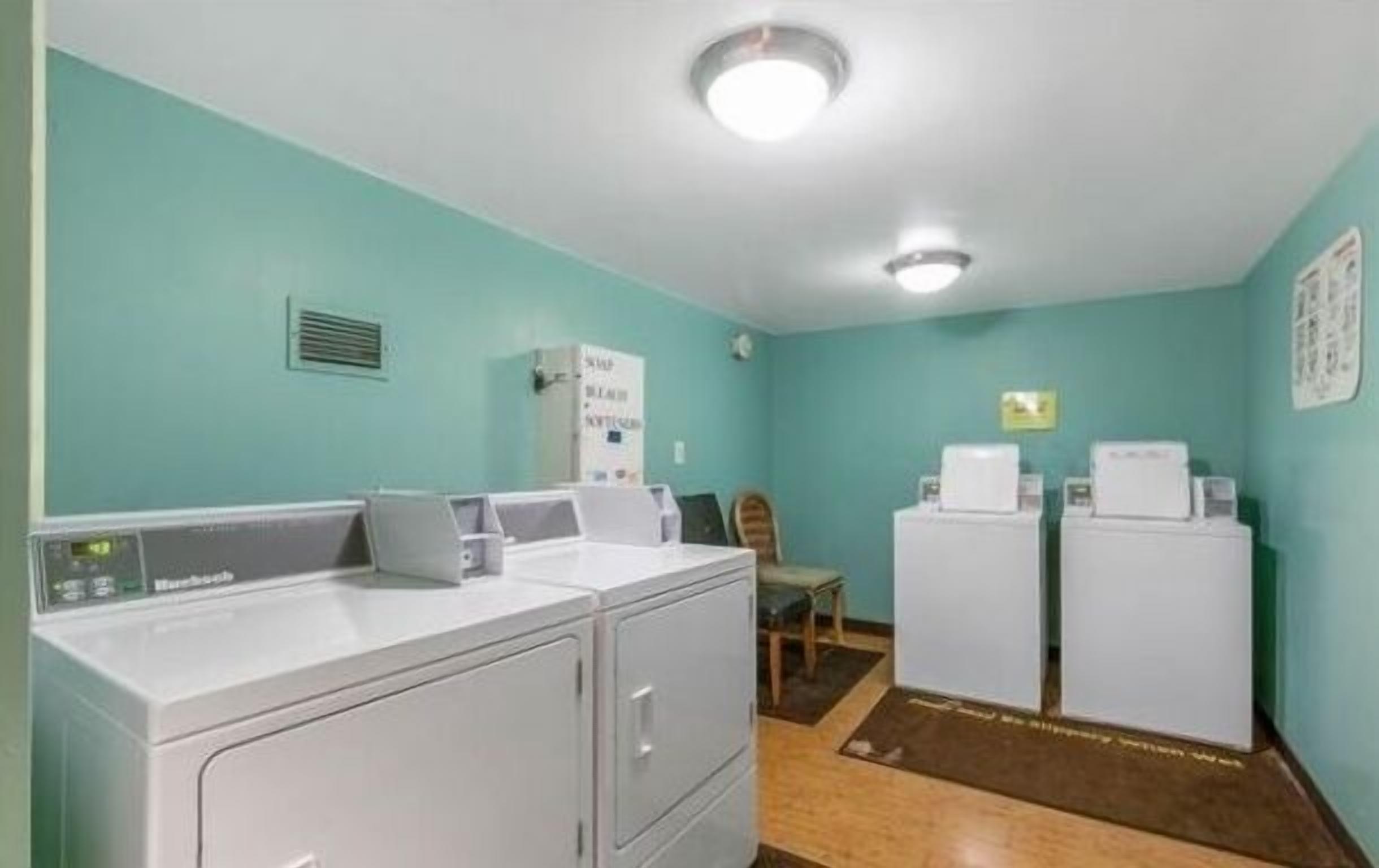 A laundry room with two washing machines, a dryer, and a wall-mounted heater.