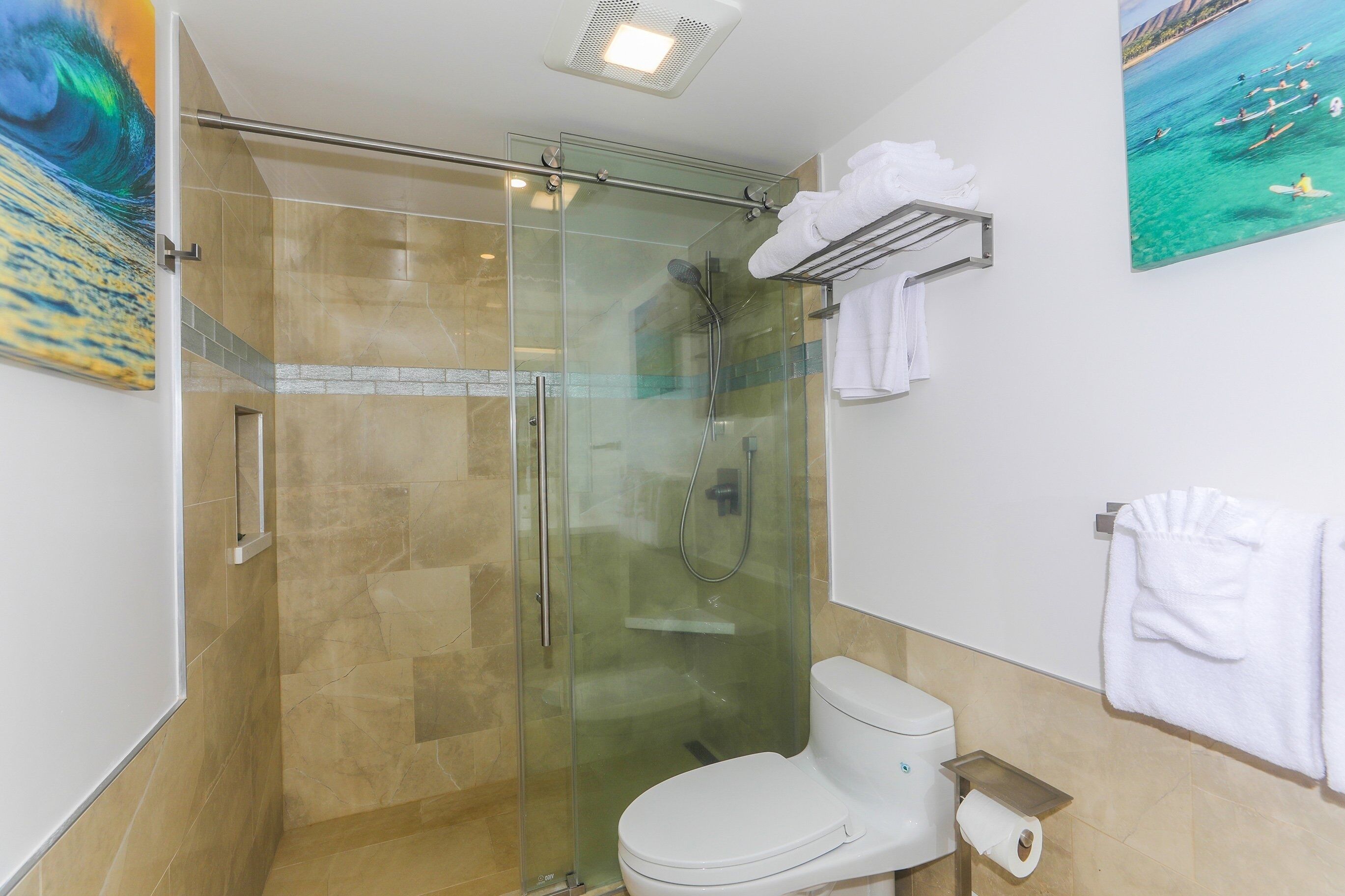 Casa de banho moderna com chuveiro envidraçado, sanita e porta-toalhas.