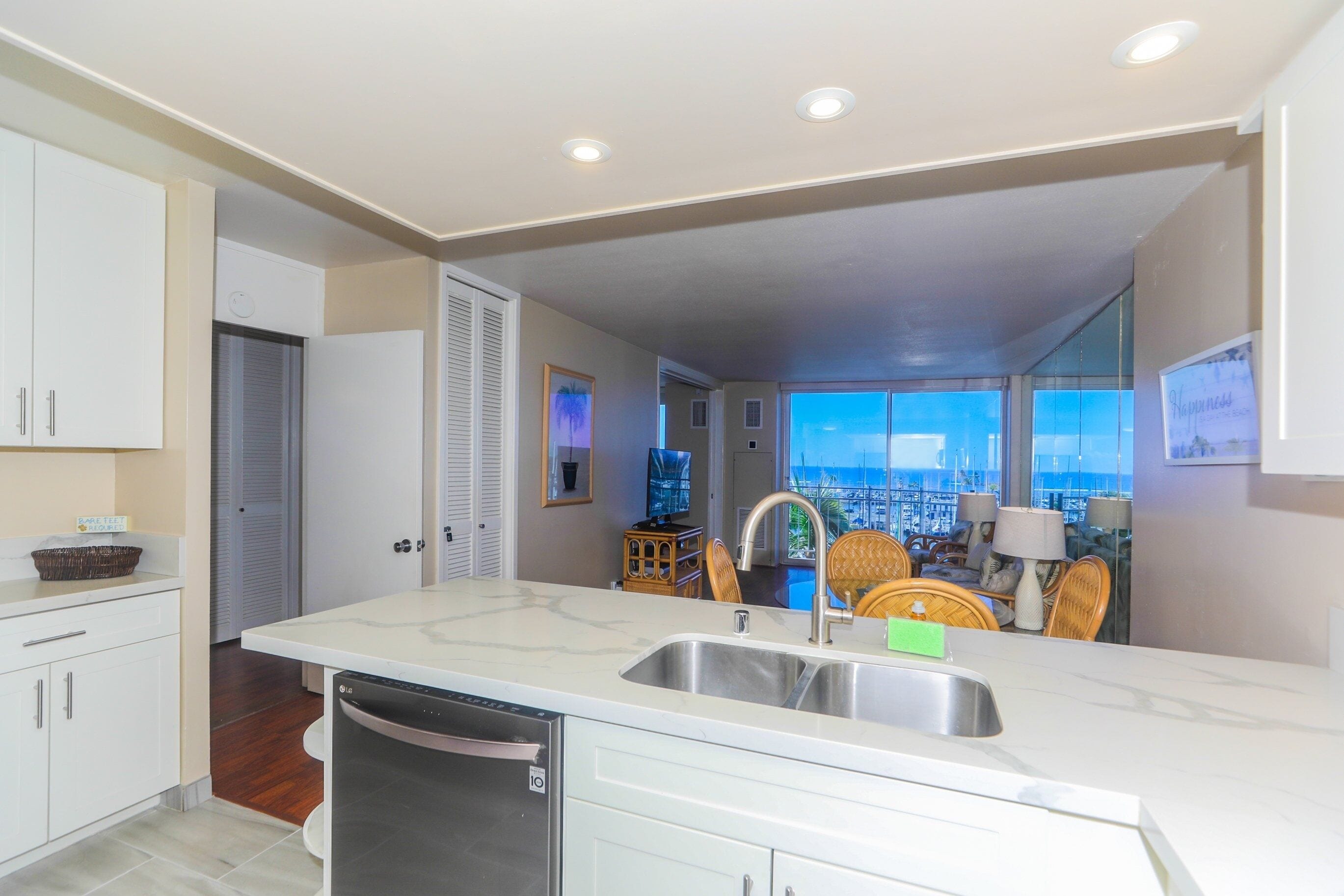 A modern kitchen with a large island, white cabinetry, and a view of the cityscape through large windows.