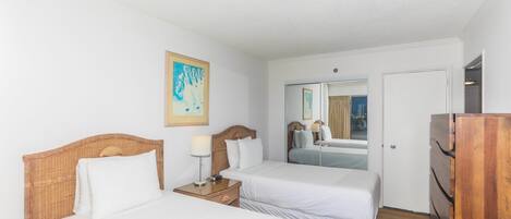 Ett hotellrum med två sängar, en byrå i trä, en spegel och en tavla på väggen.