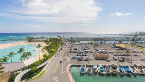 A marina with boats docked, a parking lot, and a beach with palm trees. - Ilikai Tower 943 Condo - Walk to the Beach, Shops & Restaurants! by RedAwning (Honolulu)