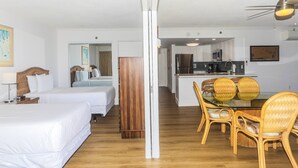 A hotel room with two beds, a wooden wardrobe, a dining table with wicker chairs, and a kitchenette with a microwave and refrigerator. - Ilikai Tower 943 Condo - Walk to the Beach, Shops & Restaurants! by RedAwning (Honolulu)