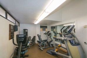Ein Fitnessstudio mit verschiedenen Trainingsgeräten, einem Spiegel und einem Schild an der Wand.