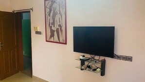 Ein Zimmer mit einem an der Wand montierten Flachbildfernseher, einem gerahmten Bild und einer Tür zu einem anderen Raum.