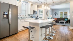Une cuisine moderne dotée d’un grand îlot central, d’appareils électroménagers en acier inoxydable et d’un coin bar avec des tabourets.