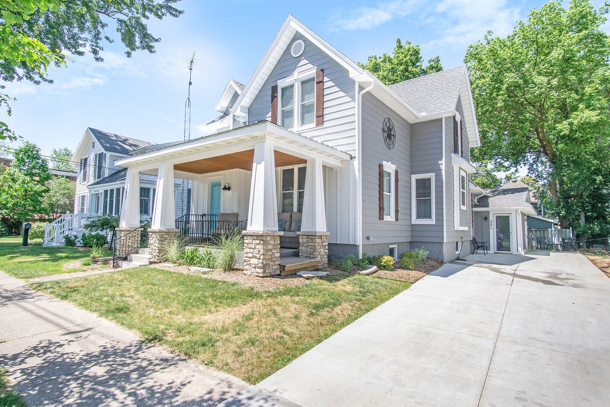 A two-story house with a covered porch, stone steps, and a well-maintained lawn.