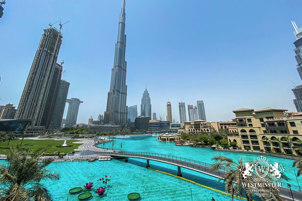 A view of the Burj Khalifa and surrounding high-rise buildings, a waterfront area with a bridge, and a pool with lotus flowers.