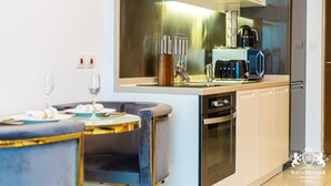 Une cuisine moderne équipée d’appareils électroménagers en acier inoxydable, d’un four encastré et d’une machine à café. On y trouve également un coin repas avec une table ronde et des chaises.