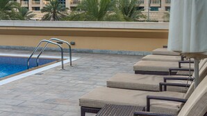 Un espace aménagé au bord de la piscine, avec des chaises longues et une piscine.