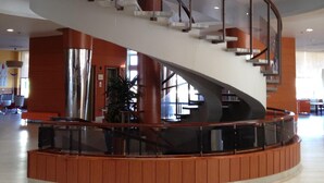 A modern interior with a curved staircase and a central column. - Evenia Zoraida Resort (Roquetas de Mar)