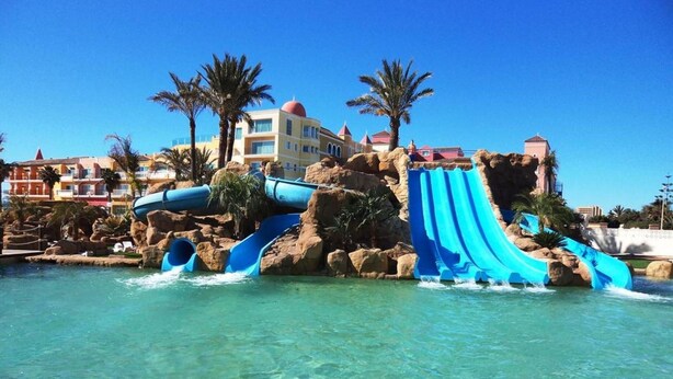 A water park with multiple slides and pools, surrounded by palm trees and buildings. - Evenia Zoraida Resort (Roquetas de Mar)