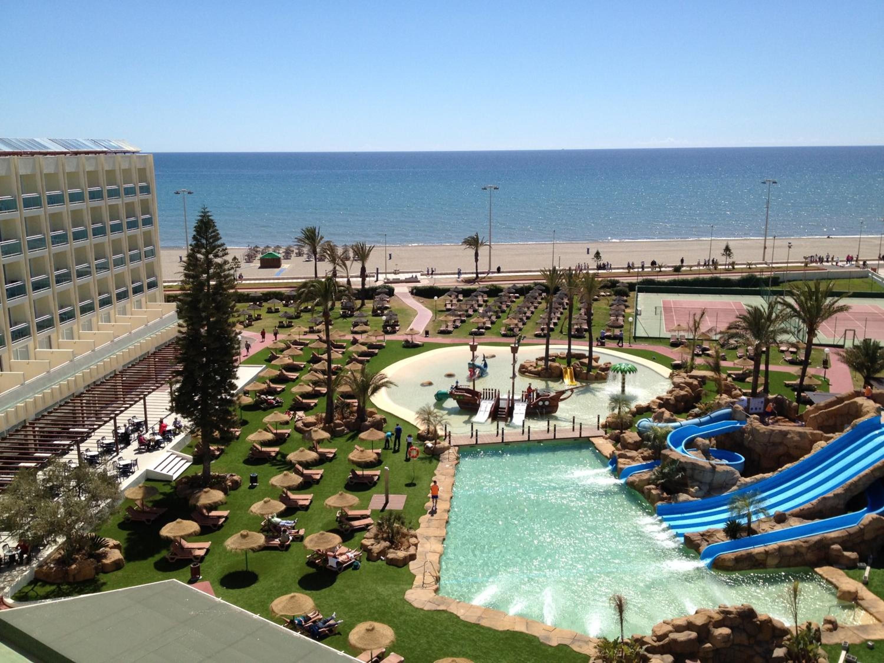 Un resort con piscina, toboganes acuáticos y vistas a la playa.
