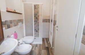 Un baño con ducha, inodoro, bidé y lavamanos.