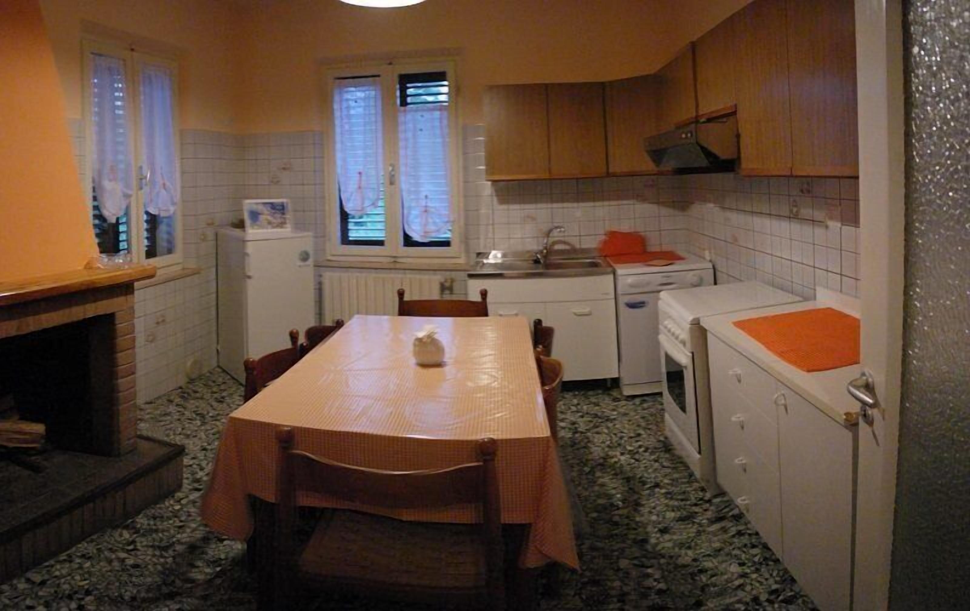 A compact kitchen with a dining table, chairs, a refrigerator, a stove, and a sink.