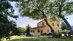 Une maison jaune à deux étages, dotée d’une piscine, entourée d’une pelouse bien entretenue et d’arbres.