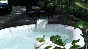 Un jacuzzi gonflable doté d’une cascade, entouré de mobilier d’extérieur et de verdure.