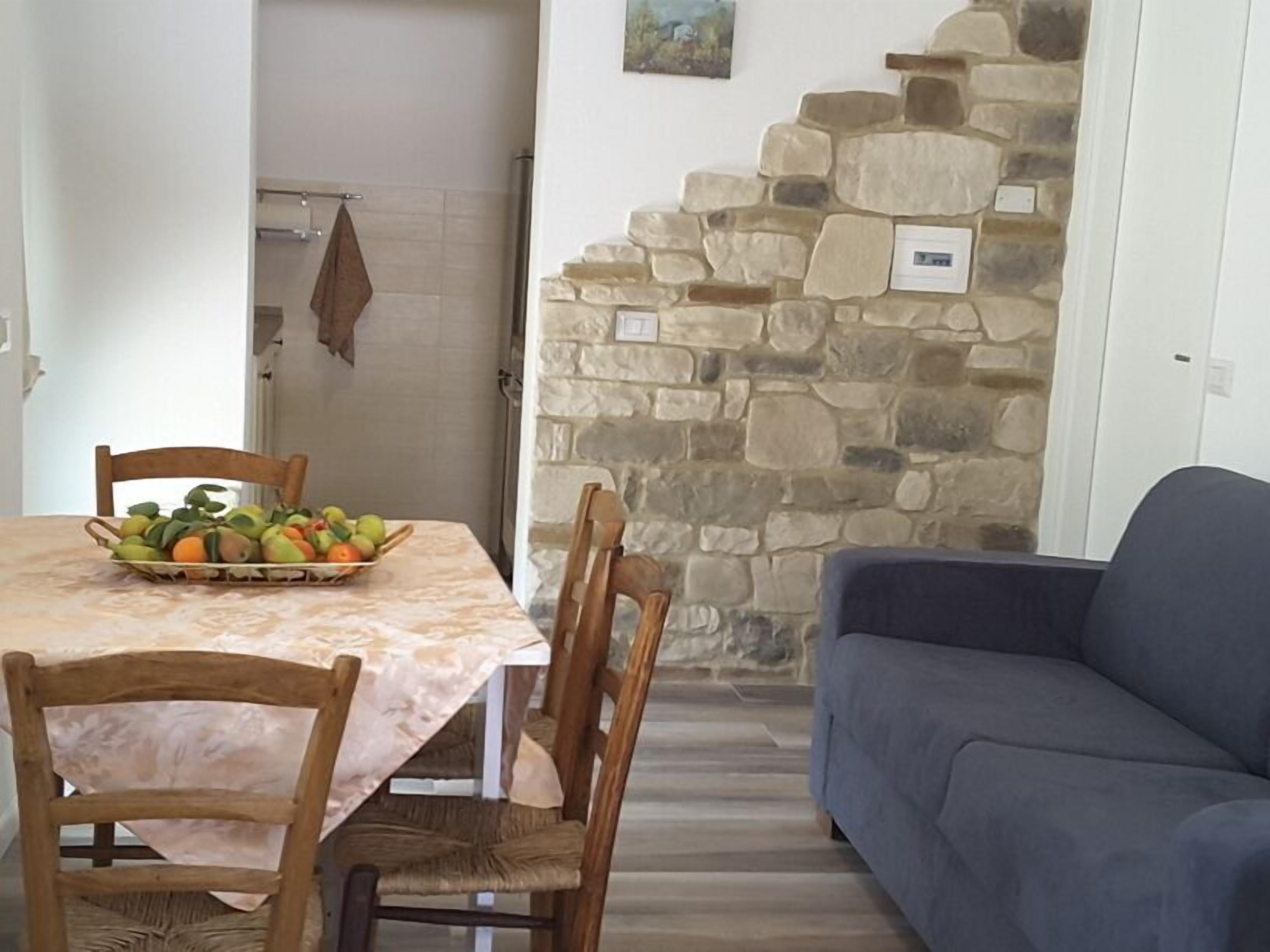 A dining area with a table set for four, a stone wall, and a blue sofa.