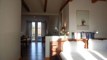 A bedroom with a bed, a desk with a lamp, a bookshelf, and a window with curtains.