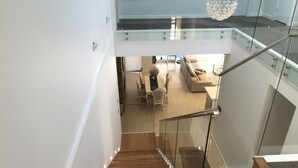 A modern interior with a wooden staircase, a glass railing, and a living area with a sofa and chairs. - Luxury big house cinema pool many guests (North Rocks)
