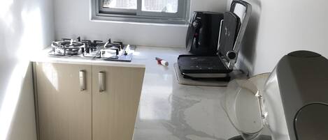 A compact kitchen with a gas stove, a coffee maker, and a microwave.