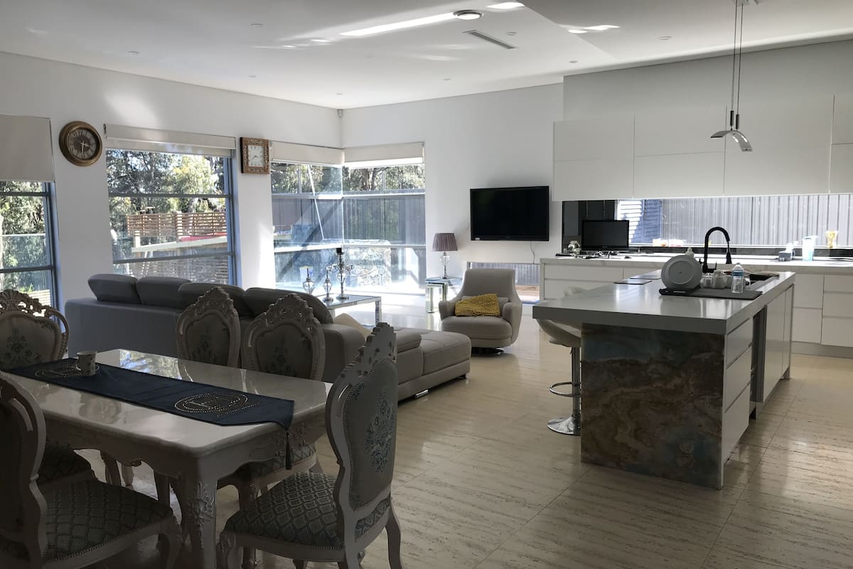 A modern living room with a dining area, a kitchen, and a large window.
