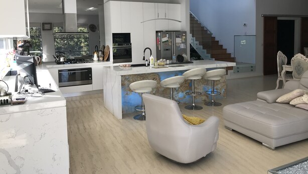 A modern kitchen with white cabinets, a large island with bar stools, a built-in oven, and a stainless steel range hood. - Luxury big house cinema pool many guests (North Rocks)