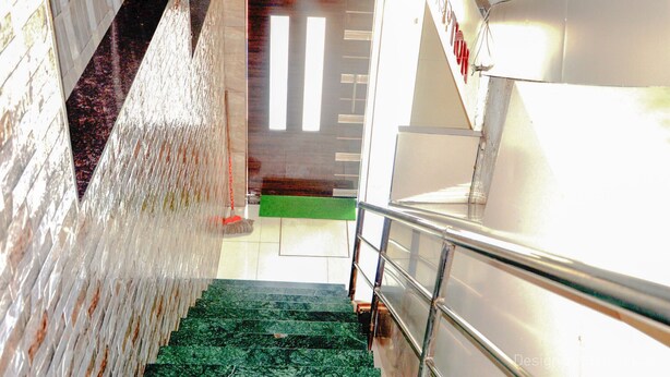 A staircase with a metal railing, a green carpet, and a door with vertical blinds. - Hotel Sarovar Grand (Panvel)