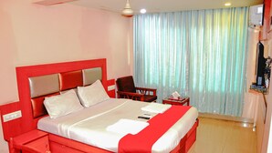 A hotel room with a large bed, a desk, a chair, and a television. - Hotel Sarovar Grand (Panvel)