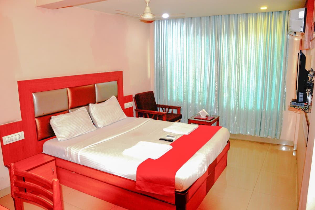 A hotel room with a large bed, a desk, a chair, and a television.