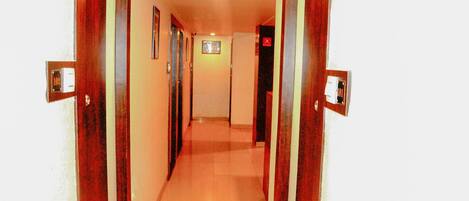 A narrow hallway with wooden doors on either side, leading to a room with a tiled floor.